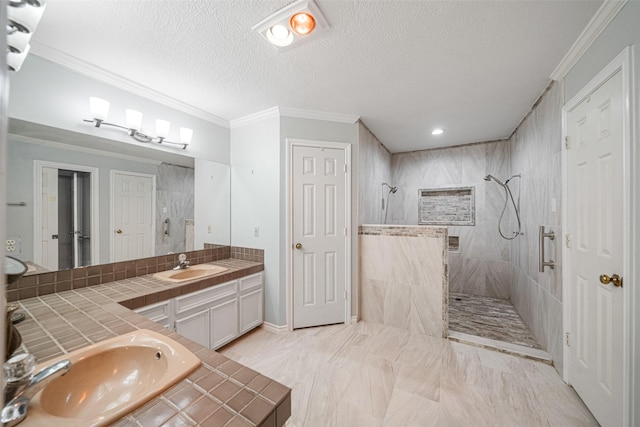 bathroom featuring tiled shower, vanity, a textured ceiling, and crown molding