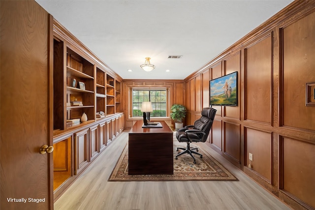 office area with built in shelves, crown molding, light hardwood / wood-style flooring, and wooden walls