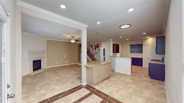 kitchen with blue cabinetry, ceiling fan, light stone countertops, a kitchen island, and ornamental molding