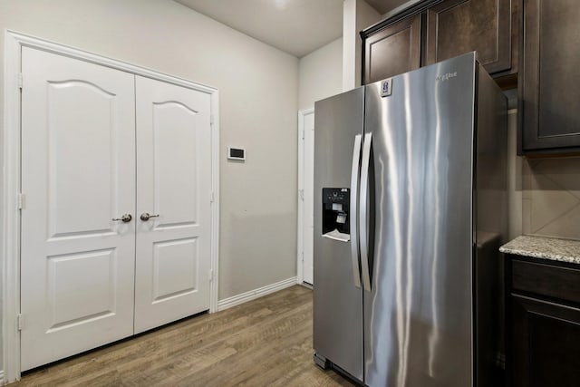 kitchen featuring light stone countertops, stainless steel fridge with ice dispenser, light hardwood / wood-style flooring, and dark brown cabinets