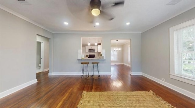 unfurnished living room with ceiling fan with notable chandelier, dark hardwood / wood-style flooring, and ornamental molding