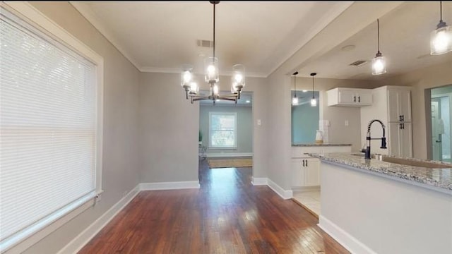 kitchen featuring pendant lighting, white cabinets, crown molding, dark hardwood / wood-style floors, and light stone countertops