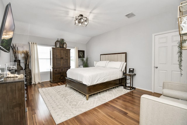 bedroom featuring lofted ceiling, dark wood-type flooring, and a chandelier