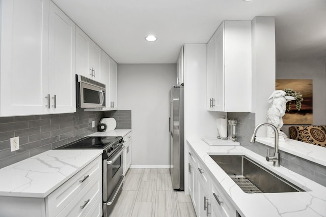 kitchen featuring backsplash, sink, light stone counters, white cabinetry, and stainless steel appliances