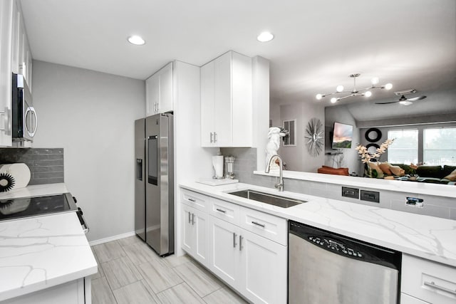 kitchen featuring light stone countertops, sink, stainless steel appliances, tasteful backsplash, and white cabinets