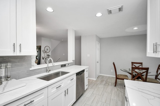 kitchen with stainless steel dishwasher, light stone counters, white cabinets, and sink