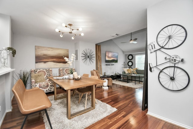 dining area featuring hardwood / wood-style floors, ceiling fan with notable chandelier, and vaulted ceiling