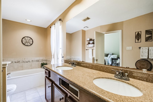 bathroom featuring toilet, vanity, tile patterned floors, and a bathing tub