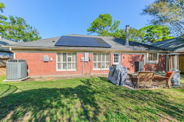 back of house with outdoor lounge area, solar panels, central AC unit, and a lawn