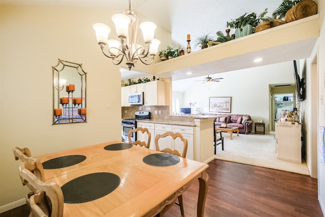 dining room with ceiling fan with notable chandelier, dark hardwood / wood-style flooring, and high vaulted ceiling