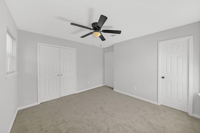 unfurnished bedroom with ceiling fan, light carpet, and a closet