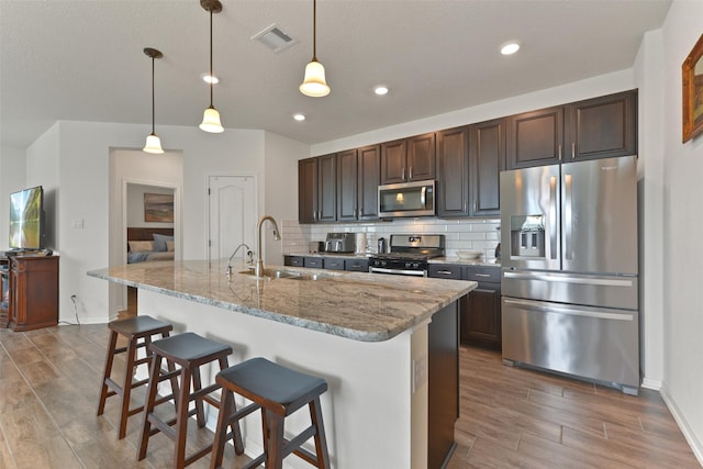 kitchen with a kitchen bar, hardwood / wood-style floors, stainless steel appliances, and sink