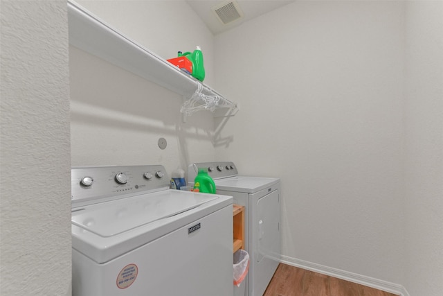 laundry room with washer and clothes dryer and light hardwood / wood-style flooring