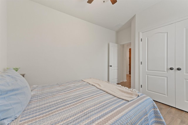 bedroom with ceiling fan, light hardwood / wood-style floors, and a closet