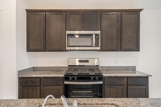 kitchen featuring dark brown cabinets, light stone counters, and stainless steel appliances