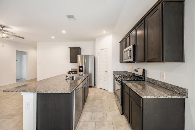 kitchen featuring stone countertops, dark brown cabinets, stainless steel appliances, and a kitchen island with sink