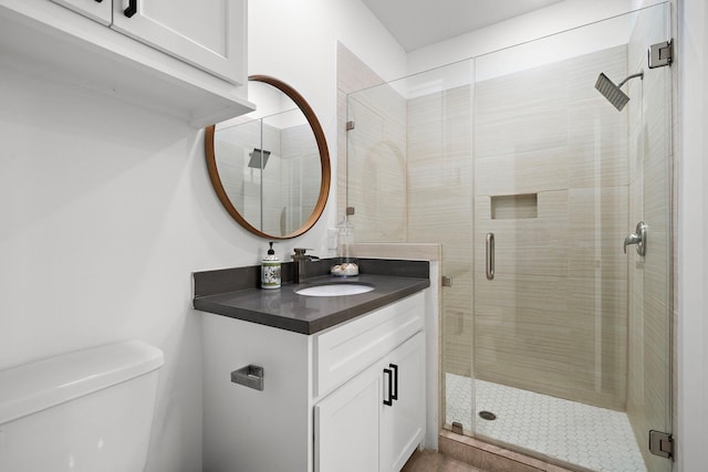 bathroom featuring vanity, toilet, and a shower with door