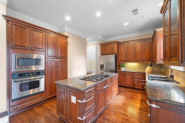 kitchen with stainless steel appliances, sink, dark stone countertops, a center island, and dark hardwood / wood-style floors