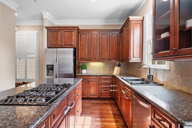 kitchen featuring appliances with stainless steel finishes, tasteful backsplash, ornamental molding, sink, and hardwood / wood-style flooring