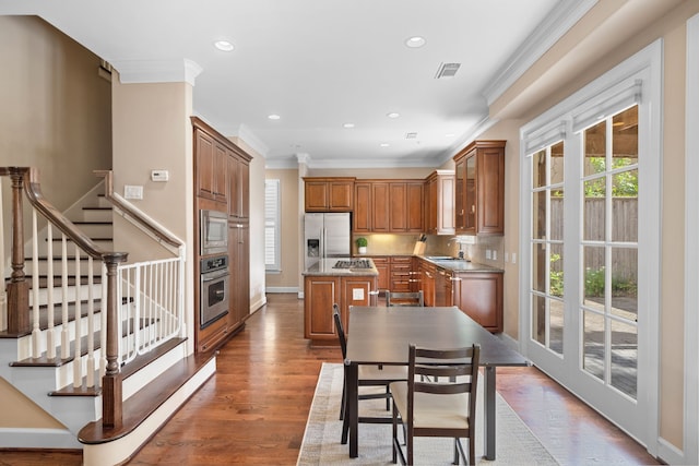 kitchen with ornamental molding, stainless steel appliances, sink, hardwood / wood-style floors, and a kitchen island