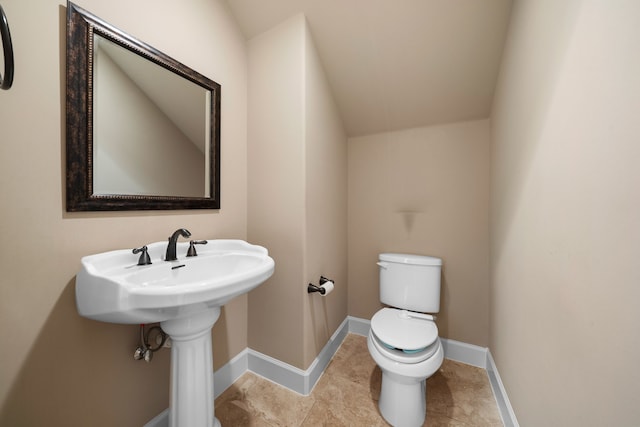 bathroom featuring toilet, tile patterned floors, vaulted ceiling, and sink