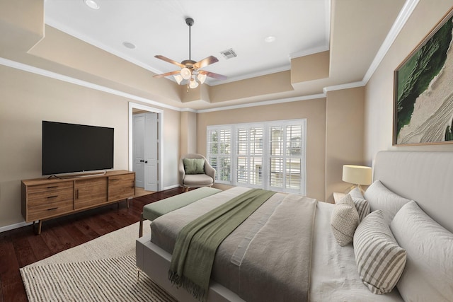 bedroom with dark hardwood / wood-style floors, ceiling fan, crown molding, and a tray ceiling