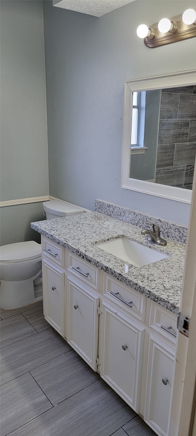 bathroom featuring vanity, hardwood / wood-style floors, a textured ceiling, and toilet