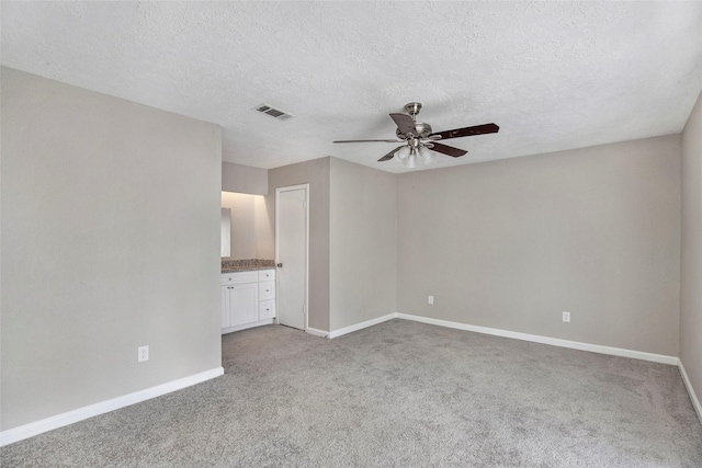 carpeted spare room featuring ceiling fan and a textured ceiling