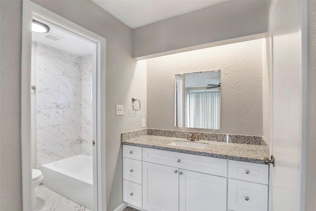 full bathroom featuring tiled shower / bath, vanity, toilet, and ceiling fan