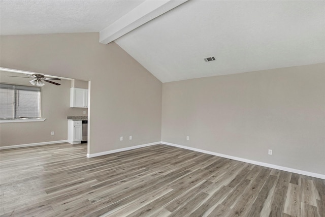 unfurnished living room featuring lofted ceiling with beams, ceiling fan, a textured ceiling, and light hardwood / wood-style flooring