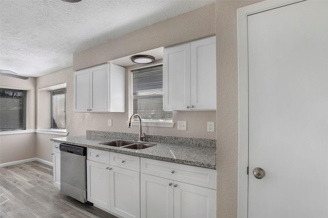 kitchen with sink, stainless steel dishwasher, dark stone countertops, light hardwood / wood-style floors, and white cabinetry