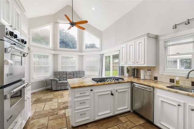 kitchen with white cabinets, high vaulted ceiling, kitchen peninsula, and appliances with stainless steel finishes