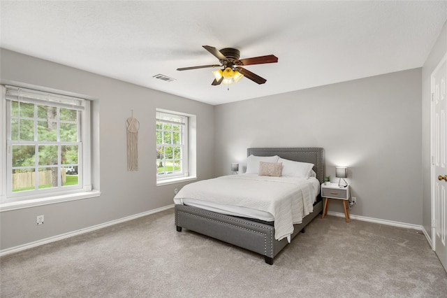 bedroom with light colored carpet, multiple windows, and ceiling fan