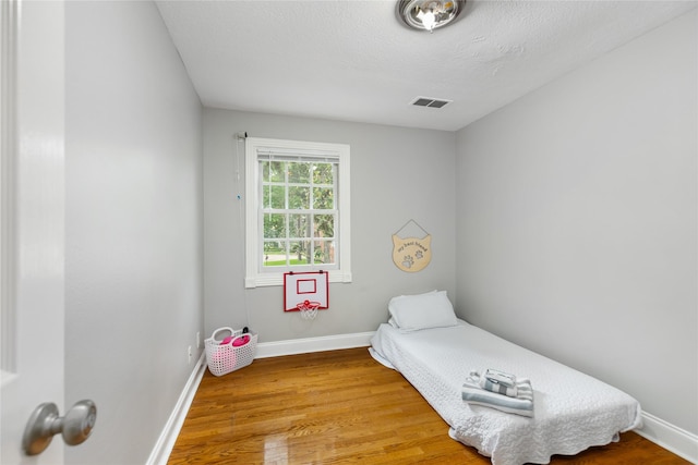 bedroom featuring hardwood / wood-style floors and a textured ceiling