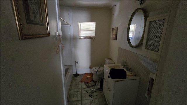 bathroom featuring a tub to relax in, vanity, and toilet