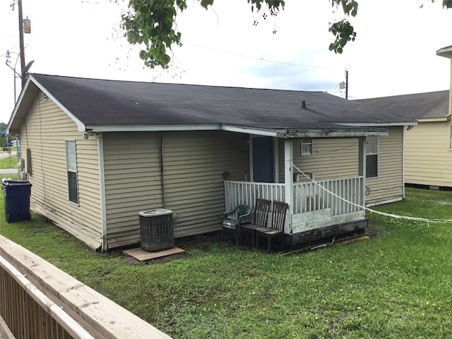 back of property featuring a porch, a lawn, and central air condition unit