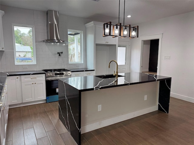 kitchen featuring wall chimney exhaust hood, a kitchen island with sink, and stainless steel range