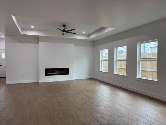 unfurnished living room with a tray ceiling and hardwood / wood-style floors