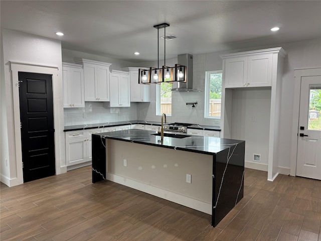 kitchen featuring dark wood-type flooring, a kitchen island with sink, and a healthy amount of sunlight