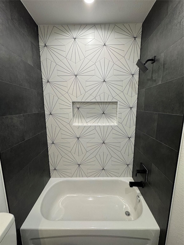 bathroom with tiled shower / bath combo and toilet