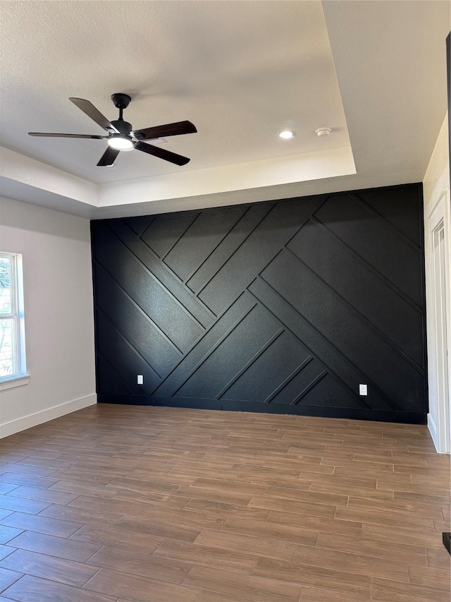 spare room with ceiling fan and a raised ceiling