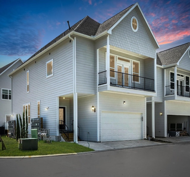 back house at dusk with central AC unit, a garage, and a balcony