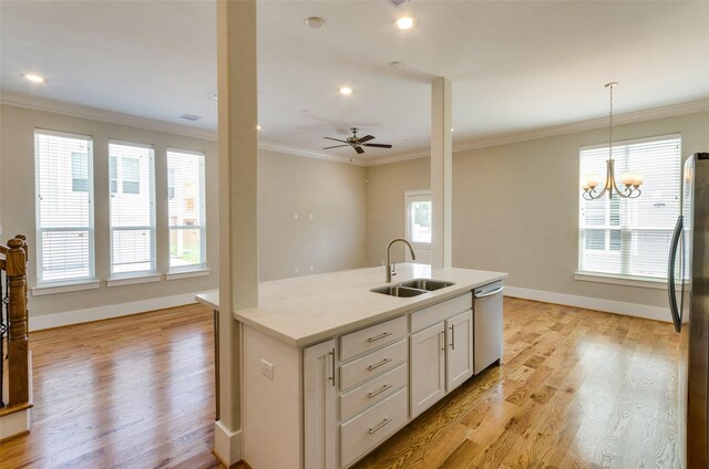 kitchen with light wood-type flooring, stainless steel appliances, sink, white cabinets, and hanging light fixtures