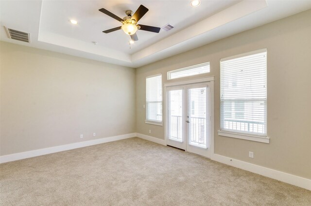 spare room featuring a tray ceiling, ceiling fan, french doors, and light colored carpet