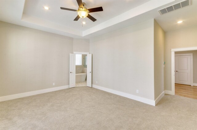 carpeted spare room featuring a raised ceiling and ceiling fan