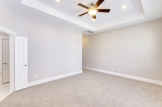 carpeted empty room featuring a raised ceiling and ceiling fan