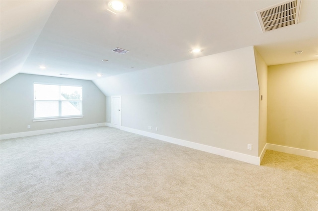 additional living space with light colored carpet and vaulted ceiling