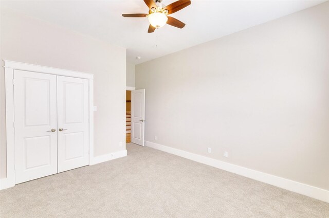 unfurnished bedroom with a closet, light colored carpet, and ceiling fan