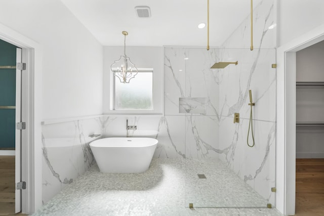 bathroom featuring tile walls, shower with separate bathtub, and an inviting chandelier