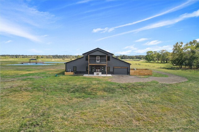 back of property with a water view, a garage, and a lawn